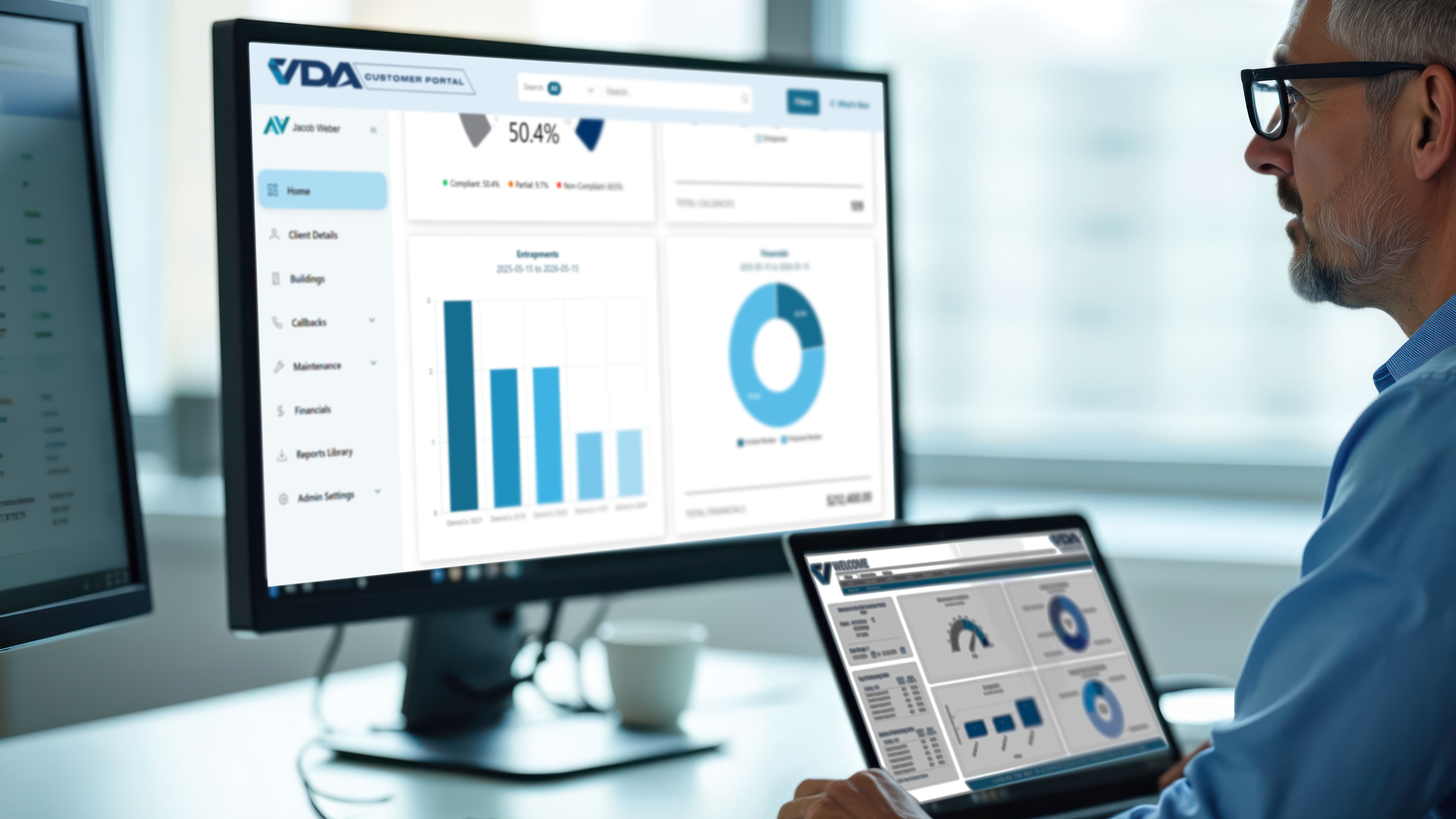 A professional sitting at his desk views a VERIFY dashboard on a laptop and large monitor to get better insights into his elevator portfolio.